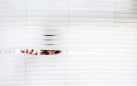woman peeking on the blinds